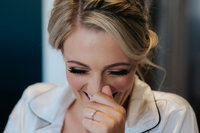 close up of bride laughing into her hand as she gets ready for her wedding