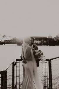 back shot of grooms hand on brides lower back on riverwalk in Milwaukee during their wedding at The Starling