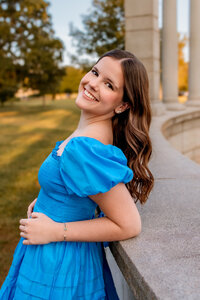 brunette teenage girl in a field in a green dress laughing