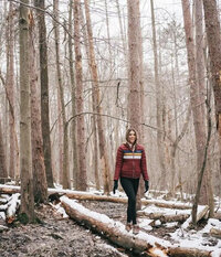 Mady Stoner strolls through the woods, wearing a red jacket and black pants, enjoying the serene natural surroundings in Ohio.