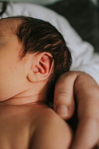 A newborn baby is held and comforted.