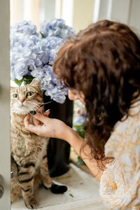 Pittsburgh wedding florist Heavenly Blooms standing in front of a vase of flowers while petting a cat