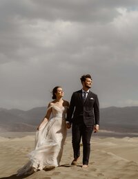 Couple holding hands in sand dunes