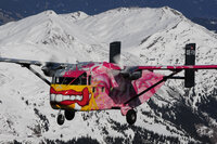 Zu sehen ist die Pink Skyvan über den verschneiten Alpen