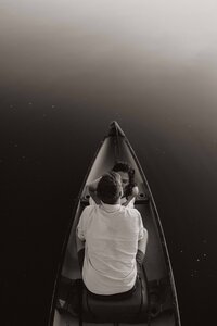 Black and white top-down view of couple in a canoe, facing each other and leaning in close.