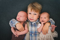 Older brother holding newborn twins — elegant family photography in Marin County