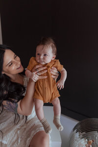 Mom embracing newborn in a family photo session in an all-white Missouri photography studio