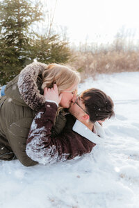 Candid winter couples session by a Michigan photographer capturing playful, cozy moments in the snow for fun-loving pairs.