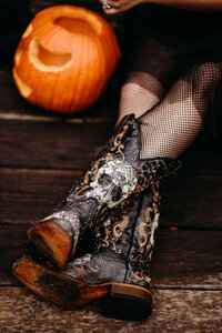 Black wedding cowboy boots featuring rhinestone skulls. There is a pumpkin in the background for the Hallowedding.