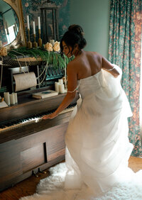 Bridal editorial session with bride at piano surrounded by floral and vintage decor in a romantic, moody setting