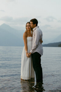 Playful couple get in the water at Lake McDonald for their engagement session