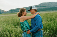 Couples photography in Rexburg Idaho. A young man is holding his girlfriend's waist, her hands around his neck. They are looking at each other and smiling.
