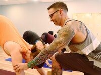 A male yoga instructor provides a hands-on therapeutic adjustment to a student at Soma Yoga Institute.