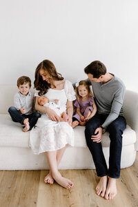 Family of five sitting on couch during photo session with Indianapolis newborn and family photographer Capturing Simplicity Photography