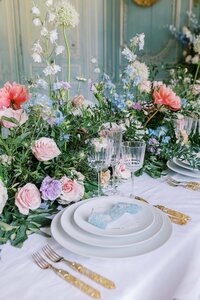 Table with a colorful flower bouquet and white silver ware