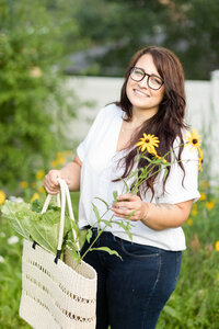 Aubre smiling, holding wildflowers outside