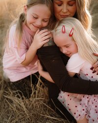 Mother and daughters at outdoor field family photo session at golden hour