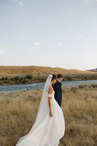 bride and groom walking along shore of river in big sky montana