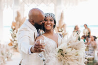 A happy couple toasts at their beachside wedding. Destined offers luxury destination wedding and honeymoon planning services, ensuring a seamless, stress-free experience for your special day.