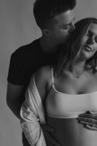 studio maternity photos with golden hour light. casual couple pose with denim jeans and white top
