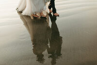 Couple walking  barefoot on the beach in tofino on their wedding day