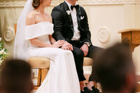 A beautiful wedding ceremony taking place in a Catholic Cathedral church, showcasing elegant decor and joyful guests, and couple are holding hands.