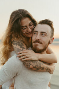 romantic and serene sunrise golden hour engagement photo of a man kissing his fiance