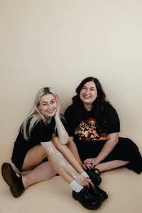 Eugene wedding planners Taressa and Clarae smiling and sitting on the floor. 