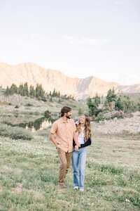 A couple smiles big while snuggling in tan sweaters in a snowy Boreas Pass