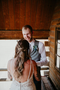 A candid wedding moment captured as the couple exchanges vows during their ceremony. The bride and groom share a joyful and emotional moment, surrounded by rustic charm and love. Chelise Boysun Photography perfectly documents the couple's special day with genuine emotion.