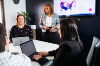 Three people around a conference table in a meeting