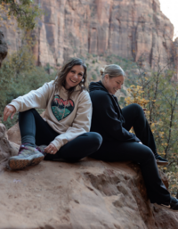 two women sitting on boulder laughing