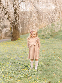 Portrait of a little girl in a dress standing in a beautiful park