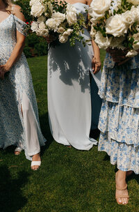 Close-up of bridesmaids and bride holding bouquets in floral dresses on a sunny lawn, captured by a Washington wedding photographer.