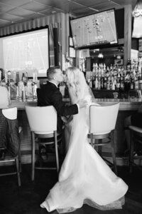 Bride and groom sitting on stools and kissing at the Pink Pony on Mackinac Island
