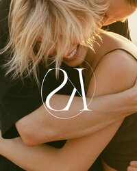 Een close up shot van een knuffel van een vrouw en een man  overgoten door een warme ondergaande zon met tevens het logo van Sharon Kastelijns Photography te zien