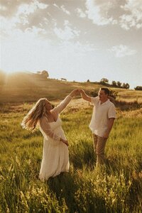 A couple dancing in a field during golden hour.