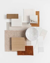 white background and stacks of different material samples, light oak wood, white marble,  deep brown red leather, neutral fabrics
