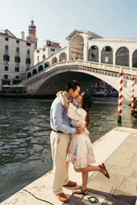 A couple kisses under Rialto bridge in Venice, Italy