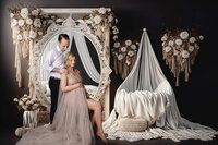 Mom posed exposing her pregnant belly on an elegant all white background photo shoot in studio.