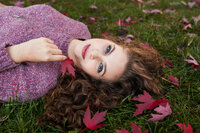 Senior portrait of girl surrounded by colorful maple leaves