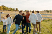 Kids running around their parents as they stand in a field