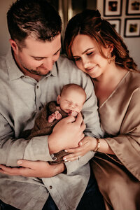 Parents snuggling their newborn baby during an in-home lifestyle photography session in Orange County