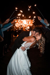 Bride and groom running through a sparkler exit with joyful expressions