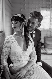 Vintage style photo of bride in Seville dress by Claire Pettibone with groom in Stephen Lawrence suit sat embracing and taking in the moment in the treehouse