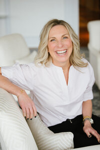 Dana smiling in white shirt on white couch