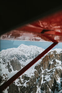view from a plane of denali in alaska, snowcapped majestic mountains under a red plane wind with sheldon air service