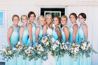 Elegant bridal squad posing for a photo in their beautiful teal dresses and florals - captured by Minnesota wedding photographer. 