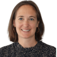 Katy Saunders Executive Director with short brown hair wearing a striped shirt and gold jewelry, smiling slightly at the camera.