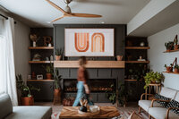 Interior lifestyle branding shot of a woman walking past a stylish fireplace setup in Breckenridge, Colorado.